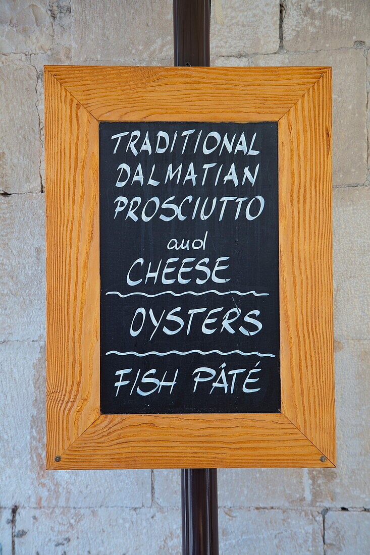 Menu board at restaurant advertises traditional Dalmatian prosciutto and cheese, oysters and fish paté, Trogir, Split-Dalmatia, Croatia