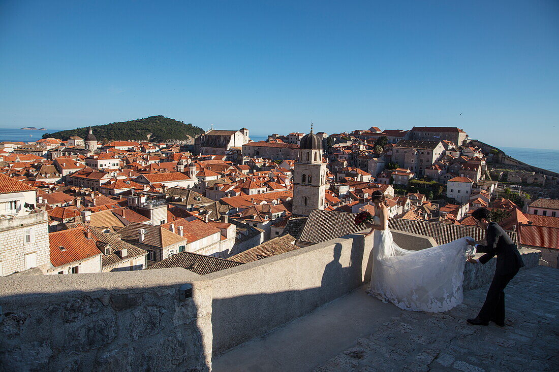 Asiatisches Hochzeitspaar posiert für Hochzeitsfotos auf Stadtmauer mit Blick auf die Altstadt, Dubrovnik, Dubrovnik-Neretva, Kroatien, Europa