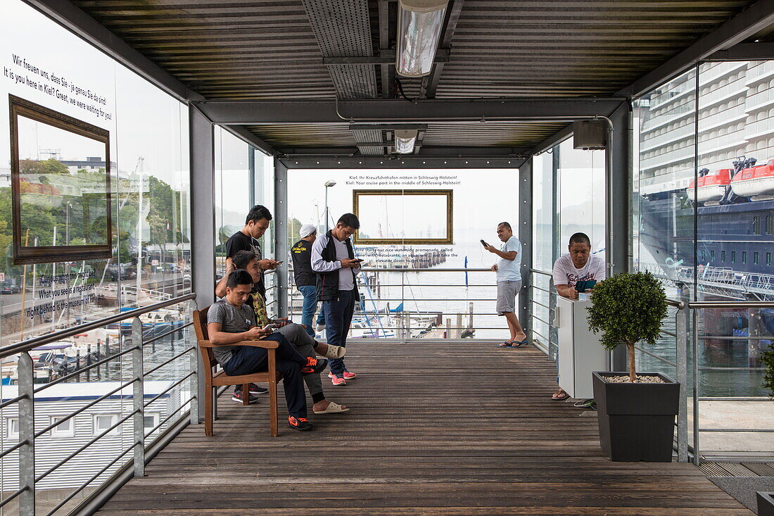 Besatzungsmitglieder von Kreuzfahrtschiff Mein Schiff 6 (TUI Cruises) nutzen kostenloses WLAN auf der Passagierbrücke am Kreuzfahrtterminal Ostseekai, Kiel, Schleswig-Holstein, Deutschland, Europa