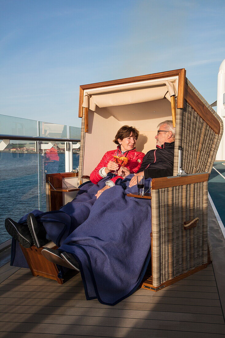 Paar genießt Getränke in einem Strandkorb auf Deck 14 von Kreuzfahrtschiff Mein Schiff 6 (TUI Cruises), Ostsee, nahe Dänemark, Europa
