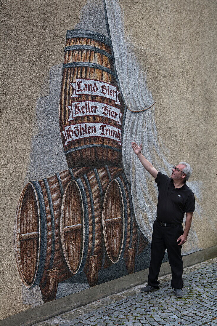 Man explains beer mural on wall of brewery museum, Pottenstein, Franconia, Bavaria, Germany
