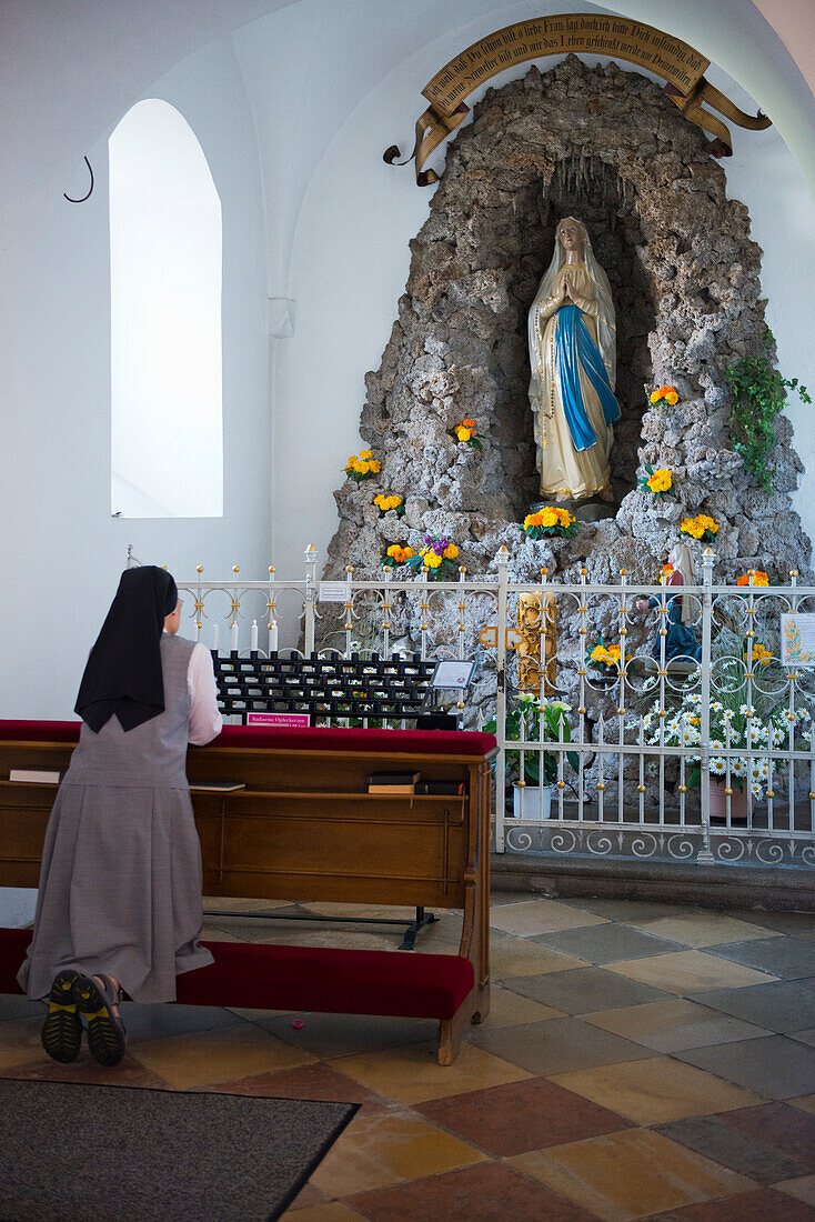 a nun is praying in a side chappel in the church of the Mallersdorf Monastery in Lower Bavaria