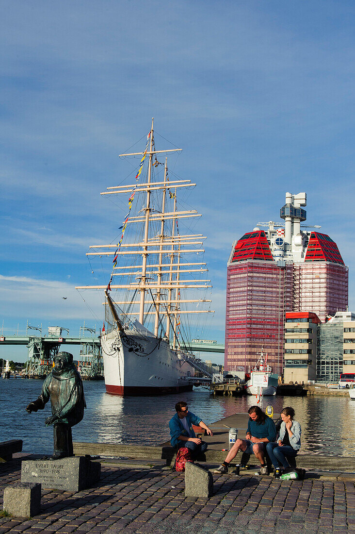 People are sitting in front of Viermastbark Viking and Skanskaskrapan skyscraper in Lilla Bommen harbor, Sweden