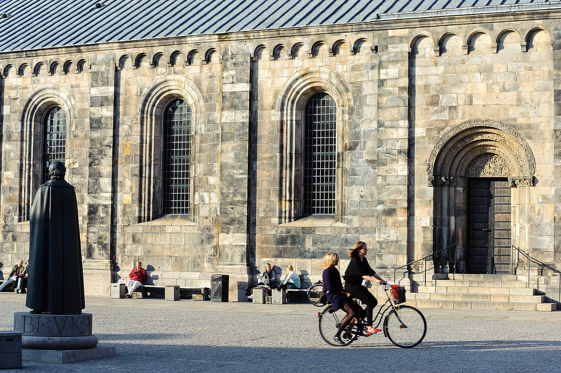 Two women ride bicycle over Cathedral square, interior Astronomical Clock, Lund, Skane, Southern Sweden, Sweden