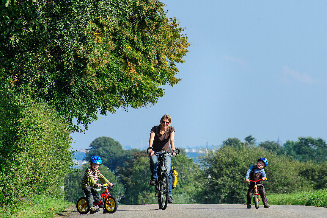 Mother is riding bicycle and children with racers on the island of Ven, Skane, Southern Sweden, SwedenSüdschweden, Schweden