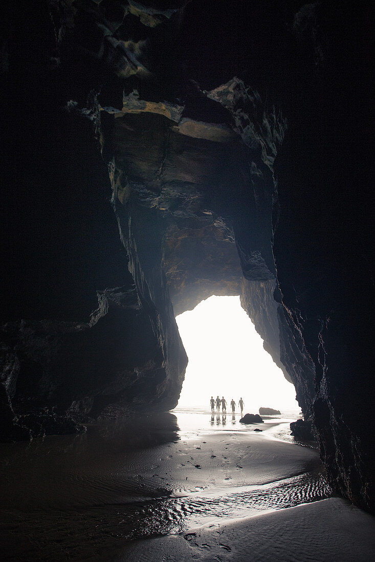 Fünf junge Männer laufen durch eine Höhle am Strand Praia da Amoreira,  Aljezur, Faro, Portugal