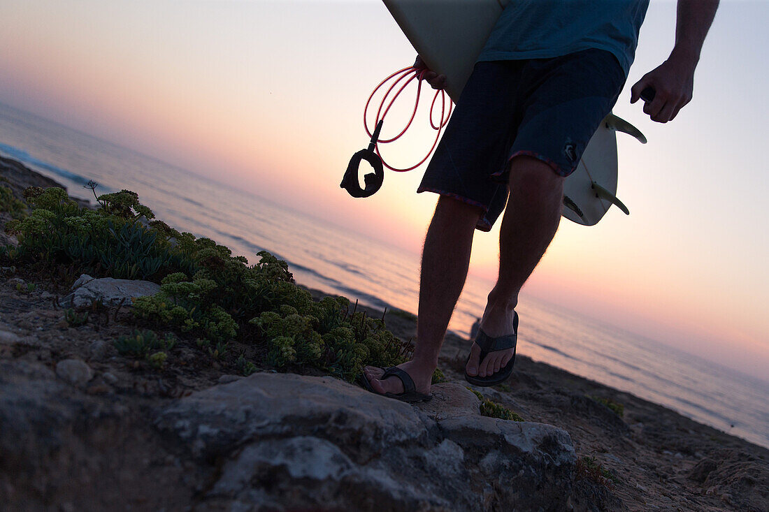 Young surfer walking with his board at the beach Praia da Amoreira,  Aljezur, Faro, Portugal