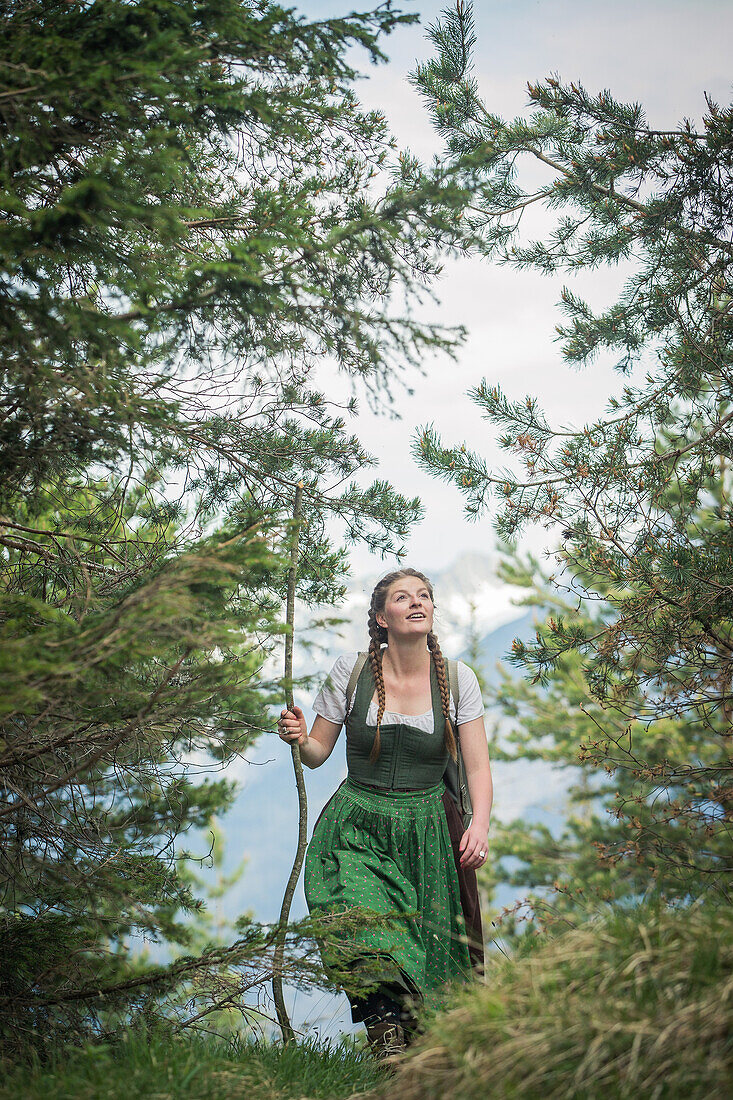 Young woman in traditional costume hiking through the forests on the Falkenstein, Pfronten, Bavaria, Germany
