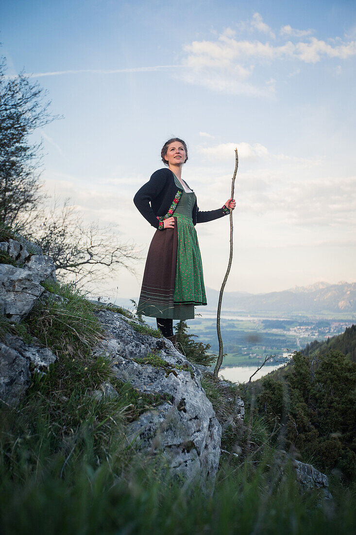 Young woman in traditional costume standing on a rock on the Falkenstein in the Allgaeu, Pfronten, Bavaria, Germany