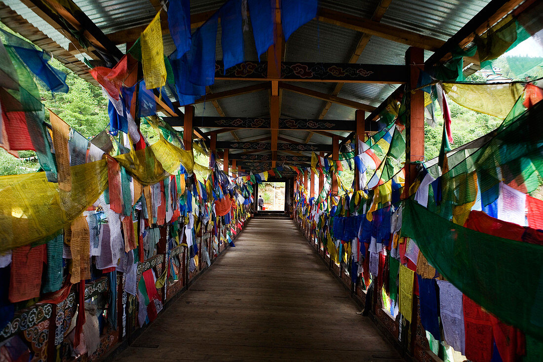Prayer flags hanging in wooden footbridge