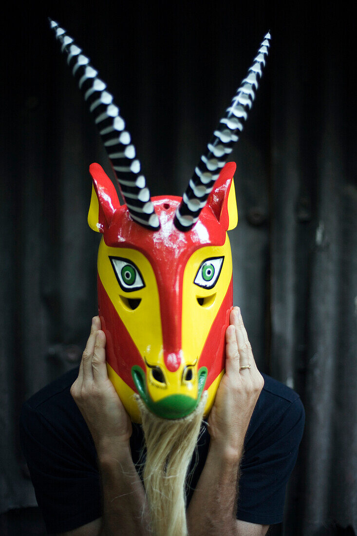 Caucasian man holding ornate goat mask