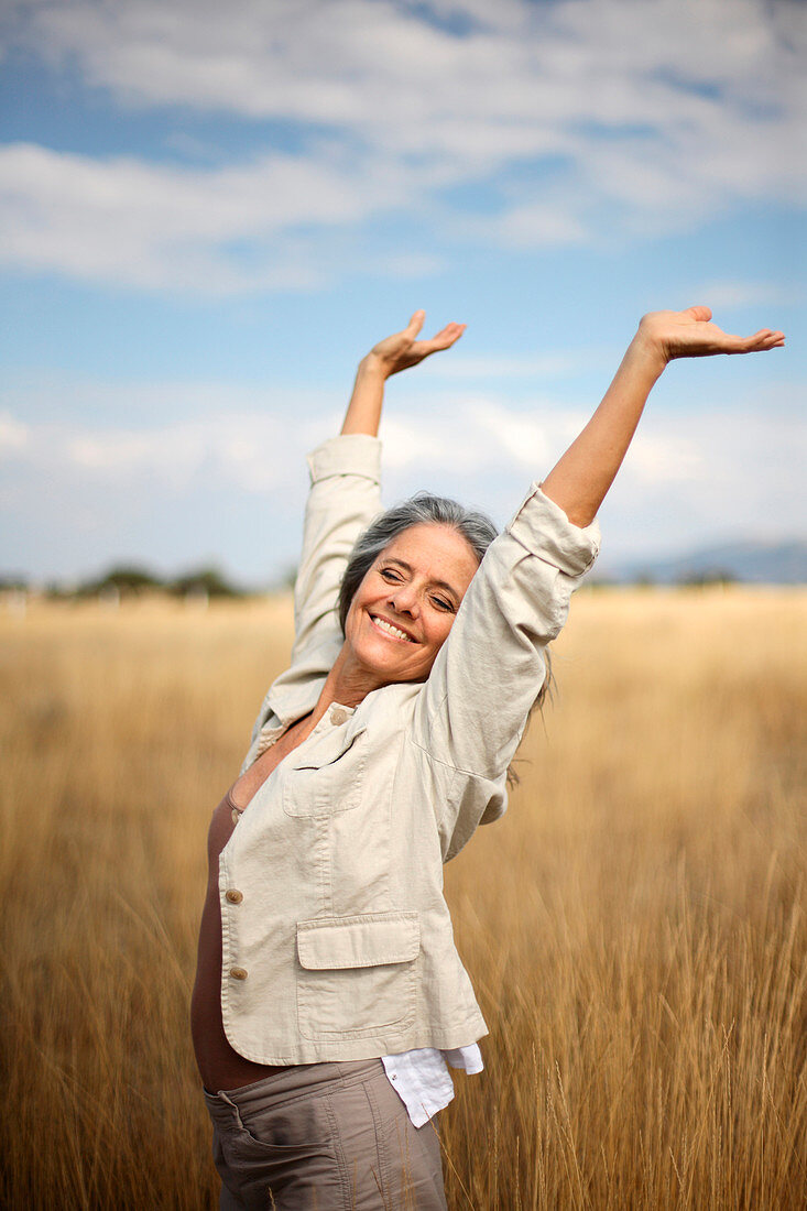 Carefree Caucasian woman standing in field of tall grass