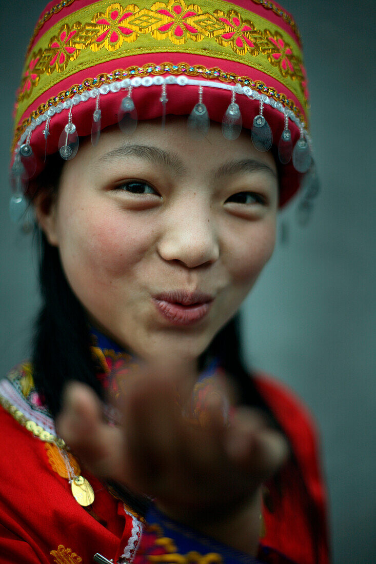 Asian girl wearing traditional hat blowing a kiss