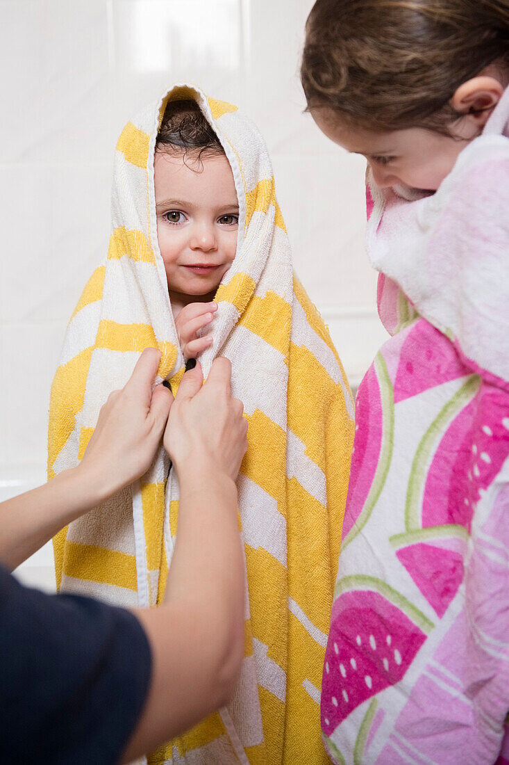 Kaukasische Mutter trocknet Töchter mit Handtüchern ab