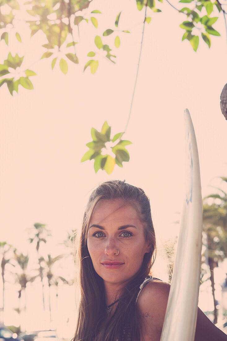Portrait of Caucasian woman holding surfboard
