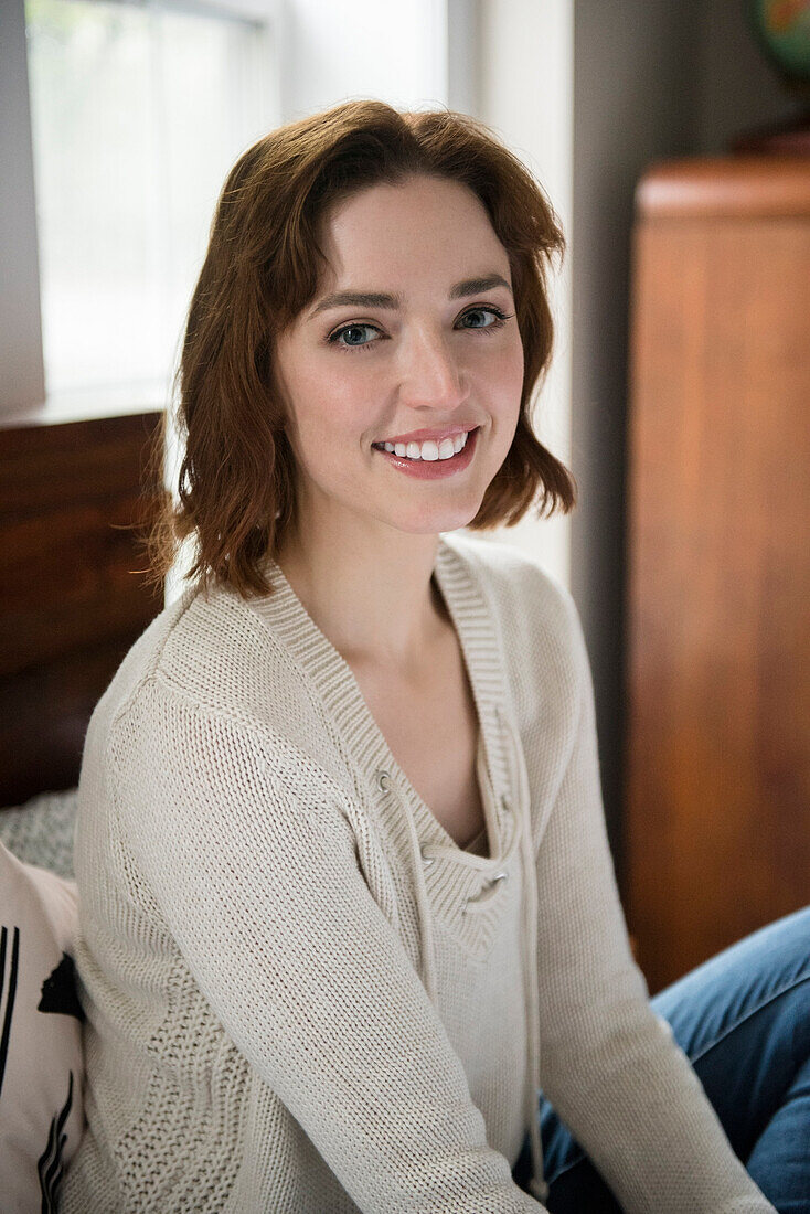 Portrait of smiling Caucasian woman sitting on bed