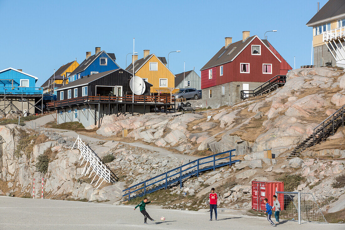 children on the soccer field in front of the colorful houses, ilulissat, greenland