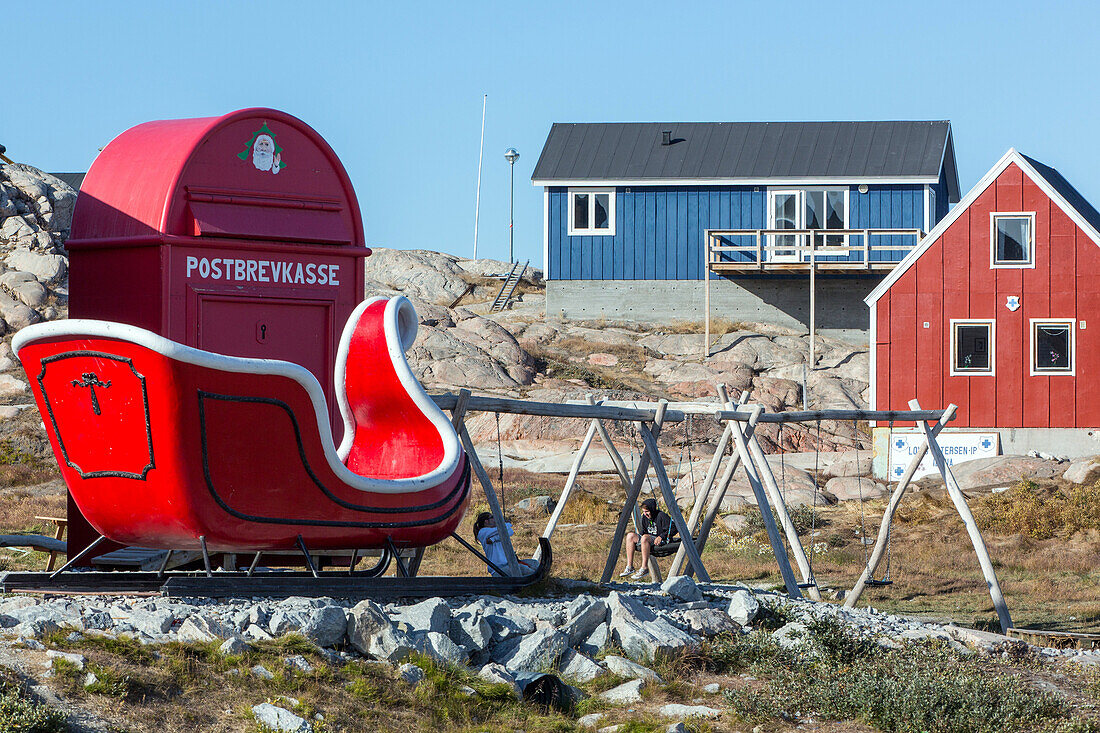 children in the playground in front of santa's sled and letterbox, ilulissat, greenland
