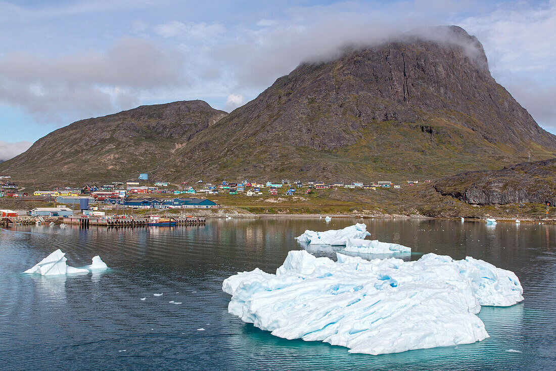 icebergs in front of the little town with colorful houses at the foot of the mountain, narsaq, greenland