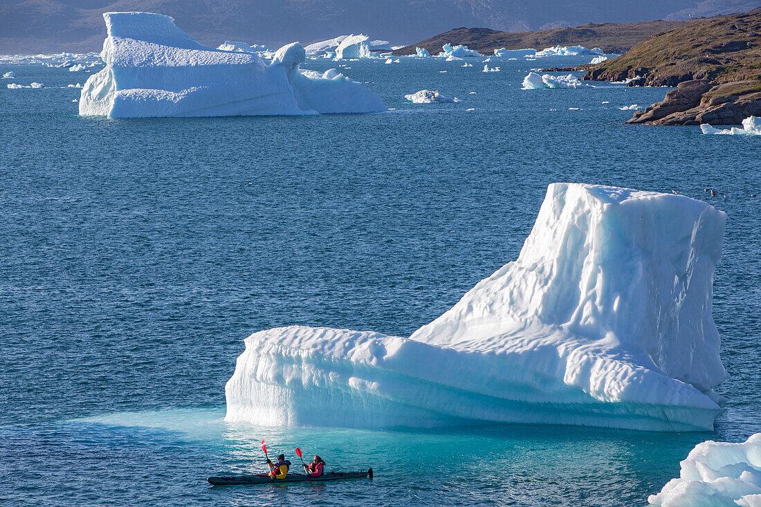 kayaking in the middle of the icebergs that separated from the glacier, fjord of narsaq bay, greenland