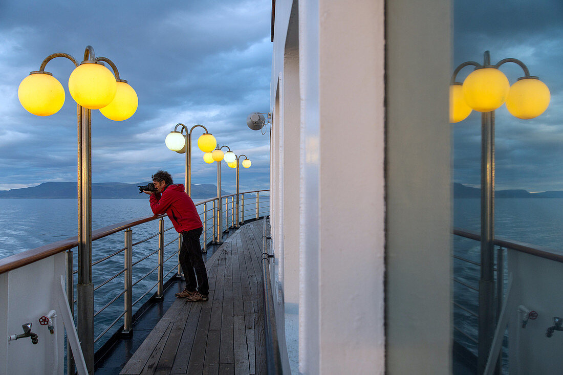 photographer on the ship's upper deck, astoria cruise ship by the icelandic coast, iceland