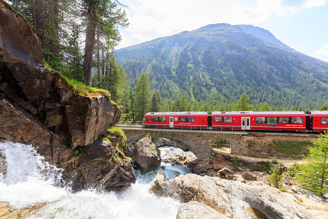 Bernina Express train beside alpine creek, Morteratsch, Engadine, Canton of Graubunden, Switzerland, Europe