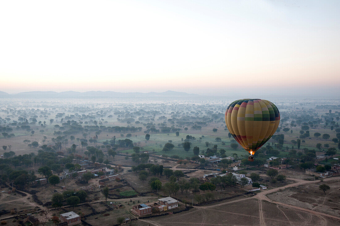 Hot air balloon in the early morning, flying over countryside and the village of Samode, Rajasthan, India, Asia