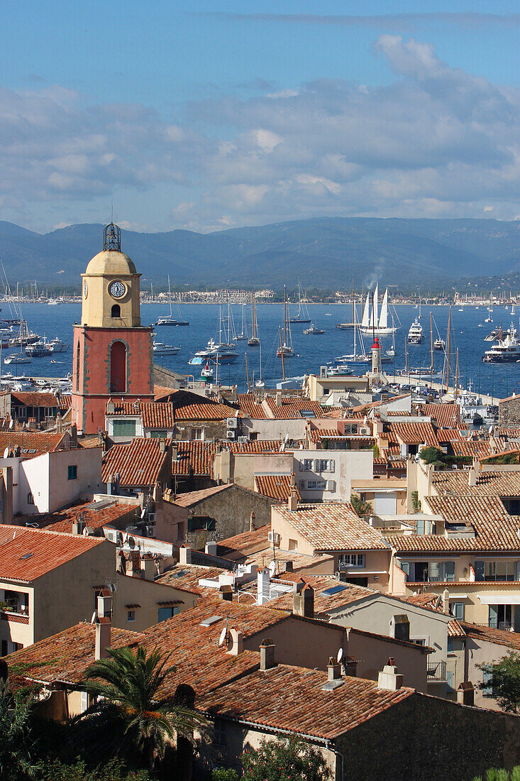 France, Var department, a large view on the old roofs and the church of the city of Saint-Tropez with in background yachting boats