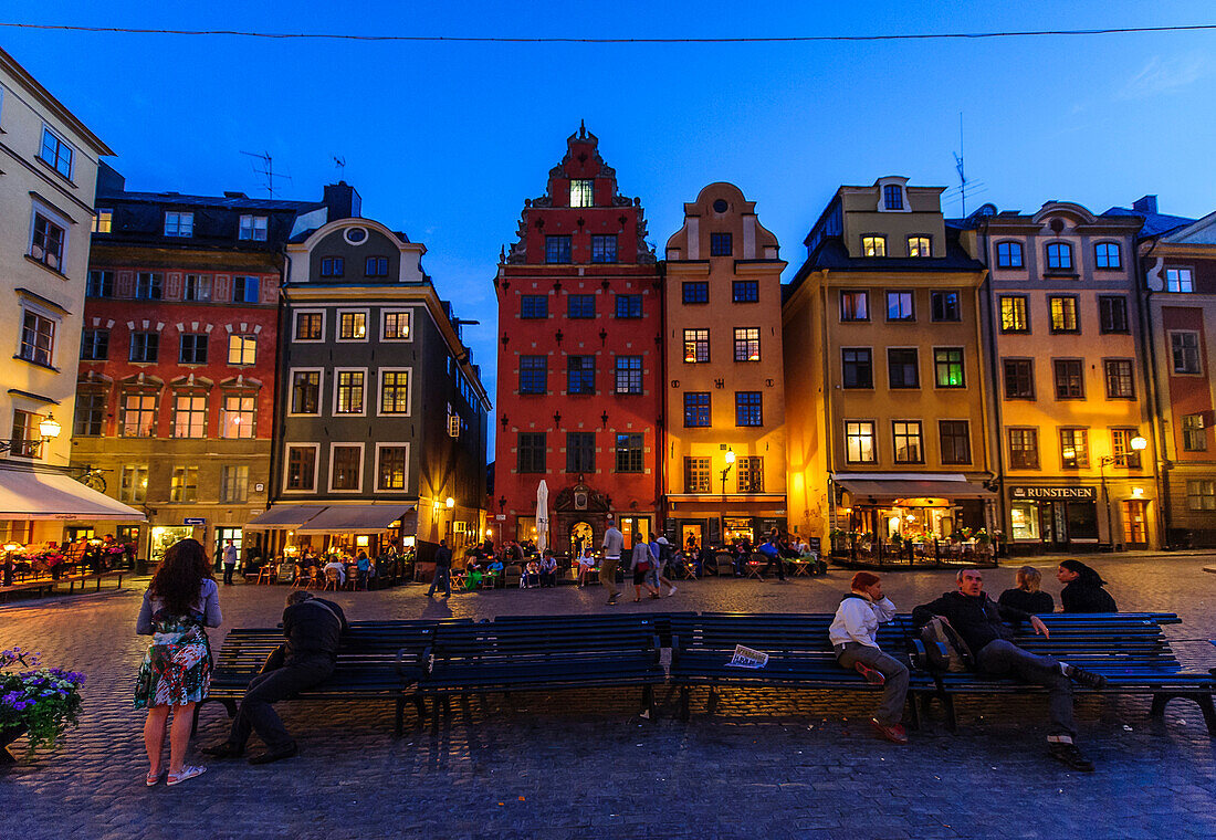 People sit on park benches in the main square Stortorget in the old town Gamla Stan, Stockholm, Sweden