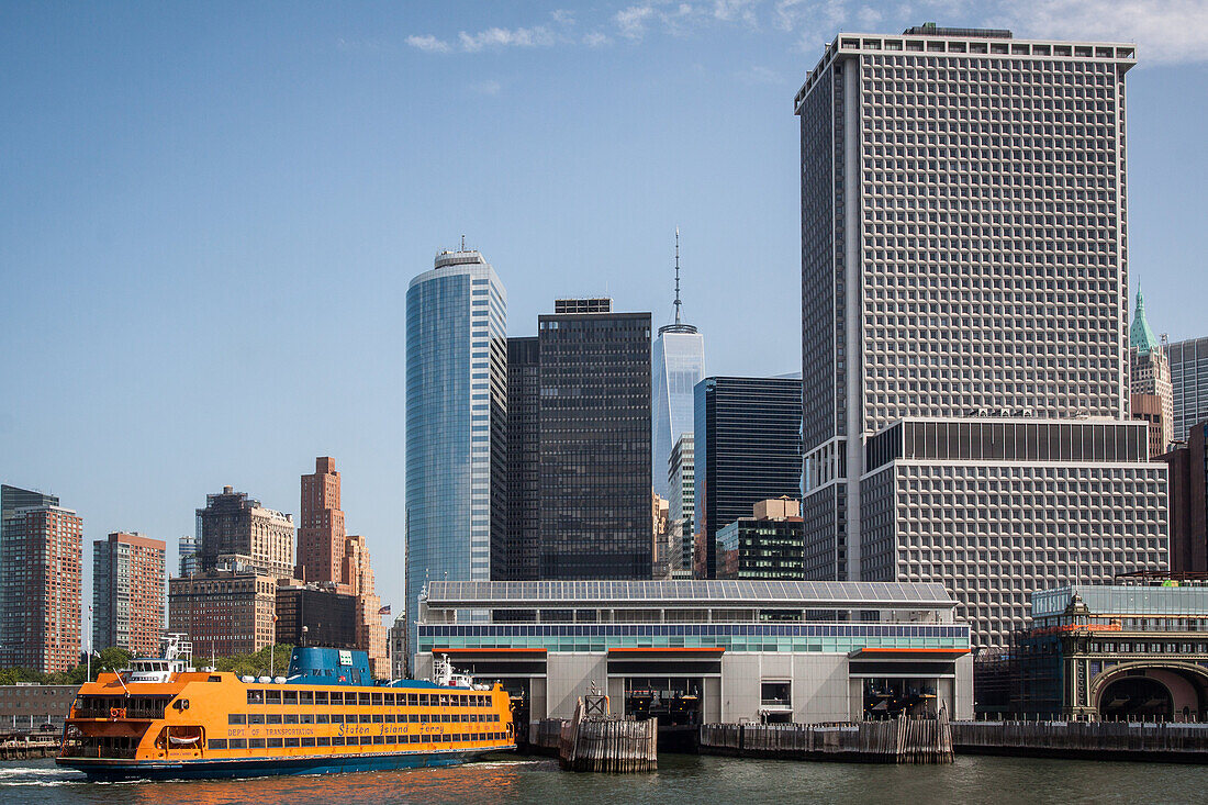 staten island ferry coming into the battery park boat terminal with a view of one world trade center and the financial district, new york harbor, new york city, state of new york, united states, usa