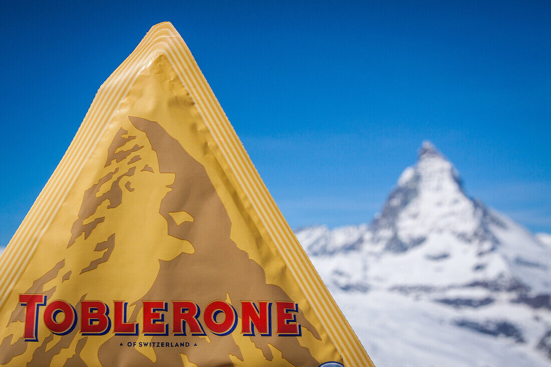 the matterhorn pictured on the wrapper from a bar of the swiss brand of chocolate toblerone with the real matterhorn in the background, advertising, ski resort, zermatt, canton of valais, switzerland