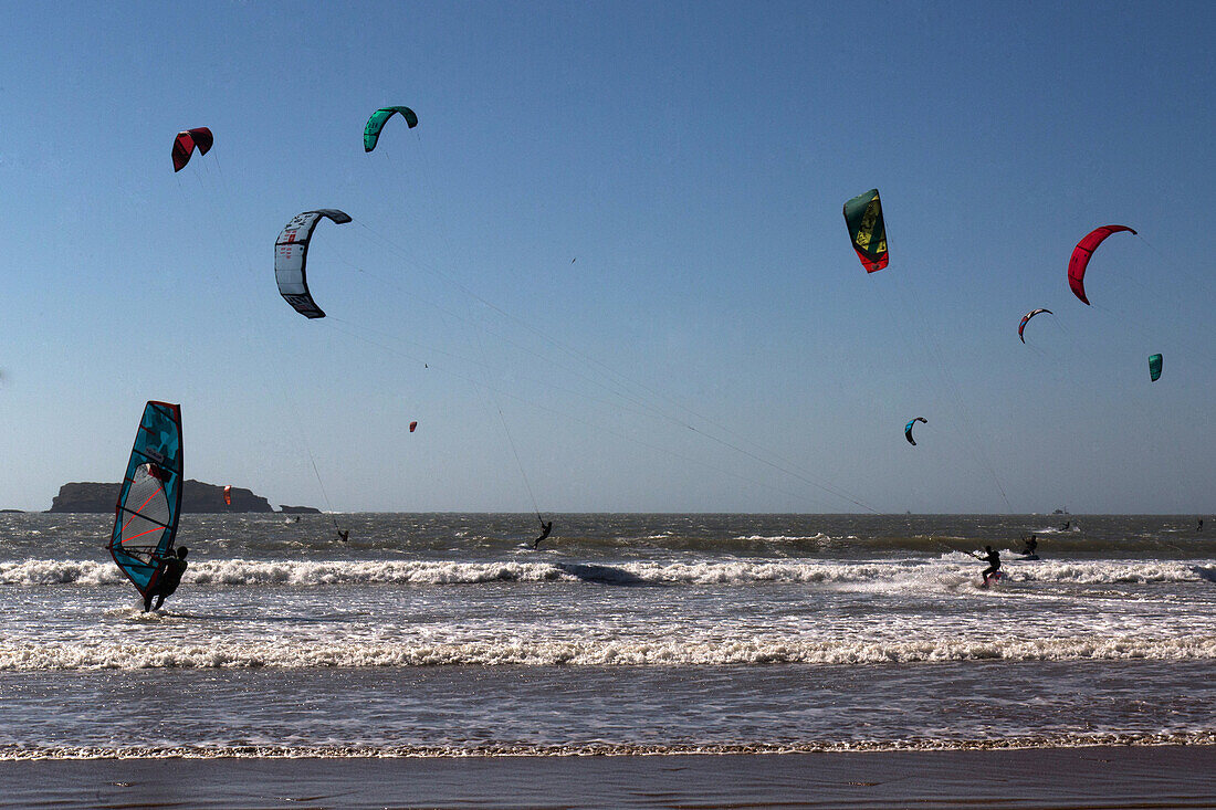 in the background, mogador island, kitesurfing, windsurfing and water sports on taghart beach, essaouira, mogador, atlantic ocean, morocco, africa