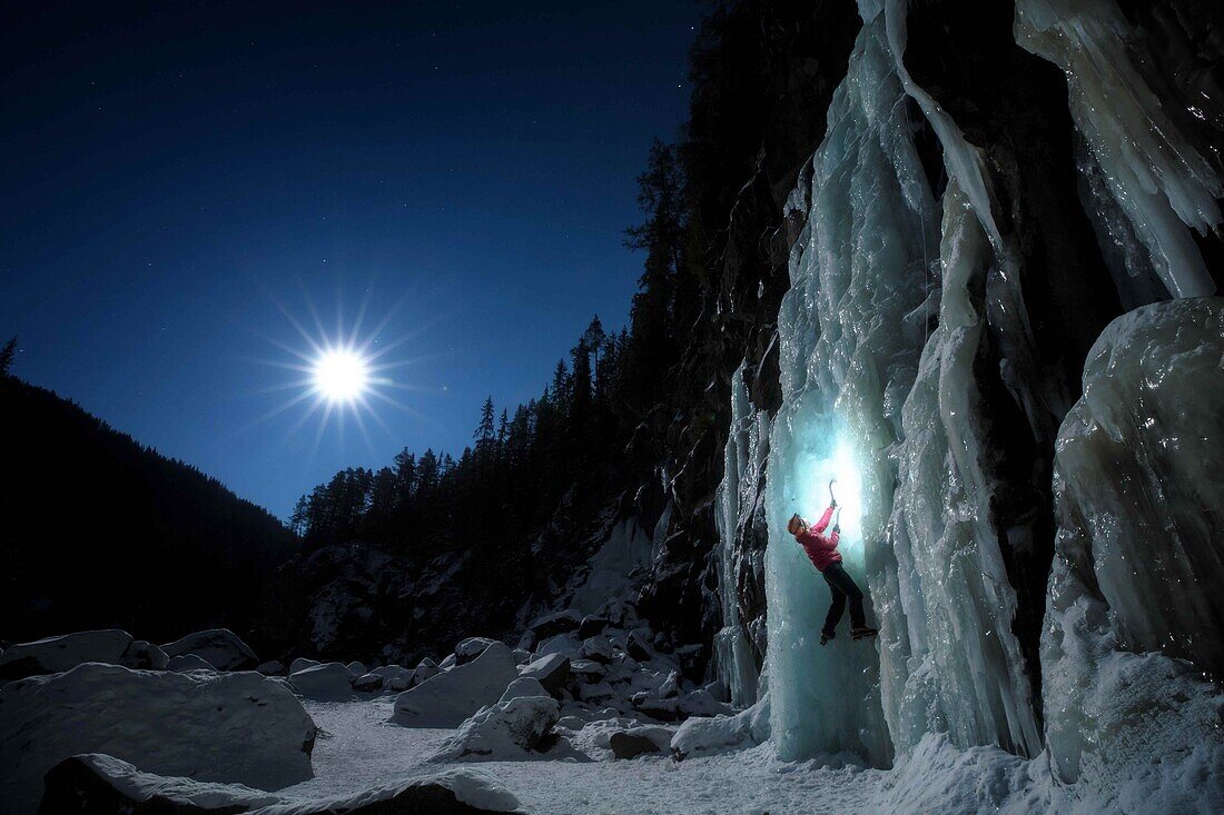 climber/mountaineer  in the moonlight climbing the ice cascades lit by his head lamp, golsjuvet falls, gol, region of hemsedal, buskerud, norway
