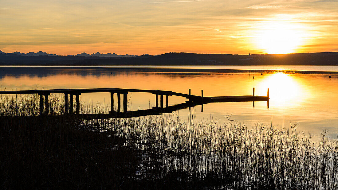 jetty at sunset with orange sky, lake Ammersee, Bavaria, Germany