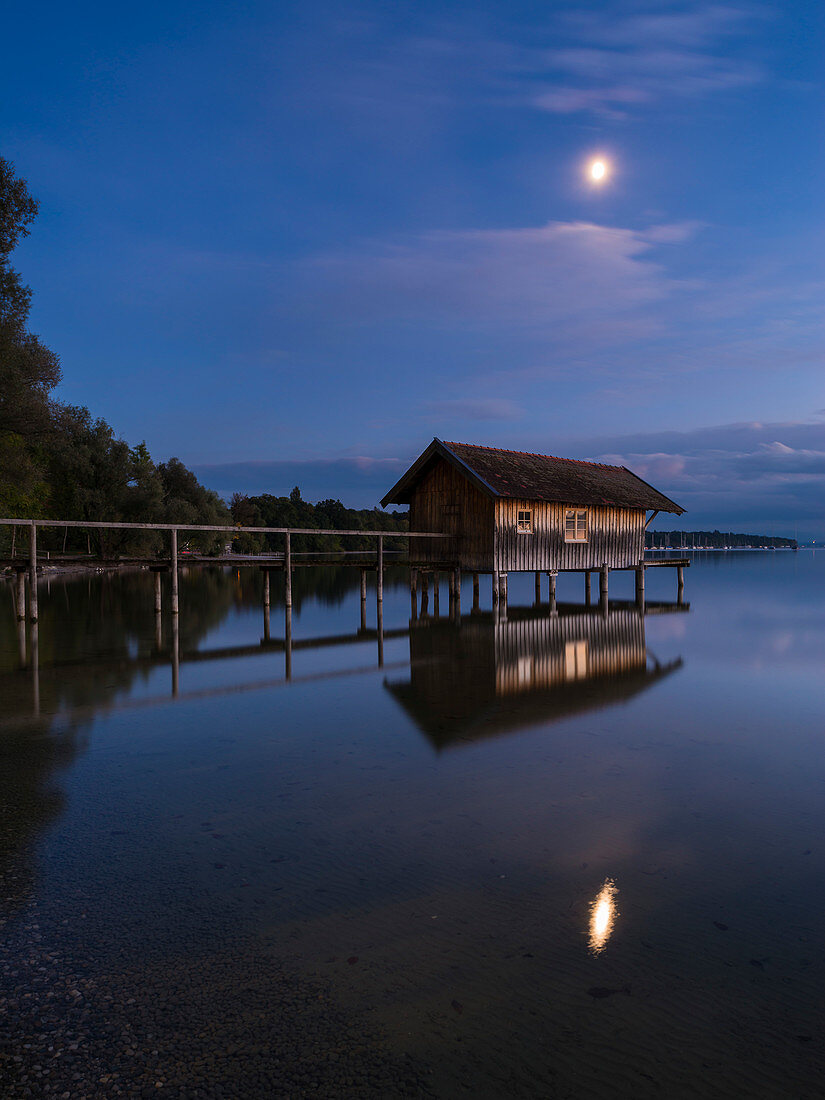 Mond über dem Bootshaus bei Stegen am Ammersee, Bayern, Deutschland