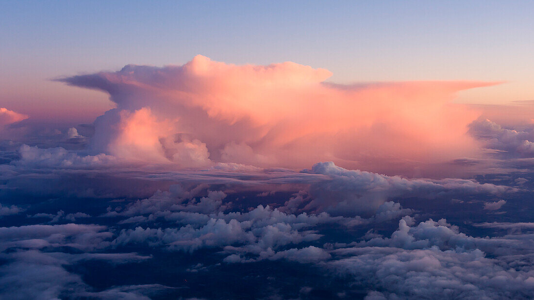 a thunderstorm is painted in pink light during sunset