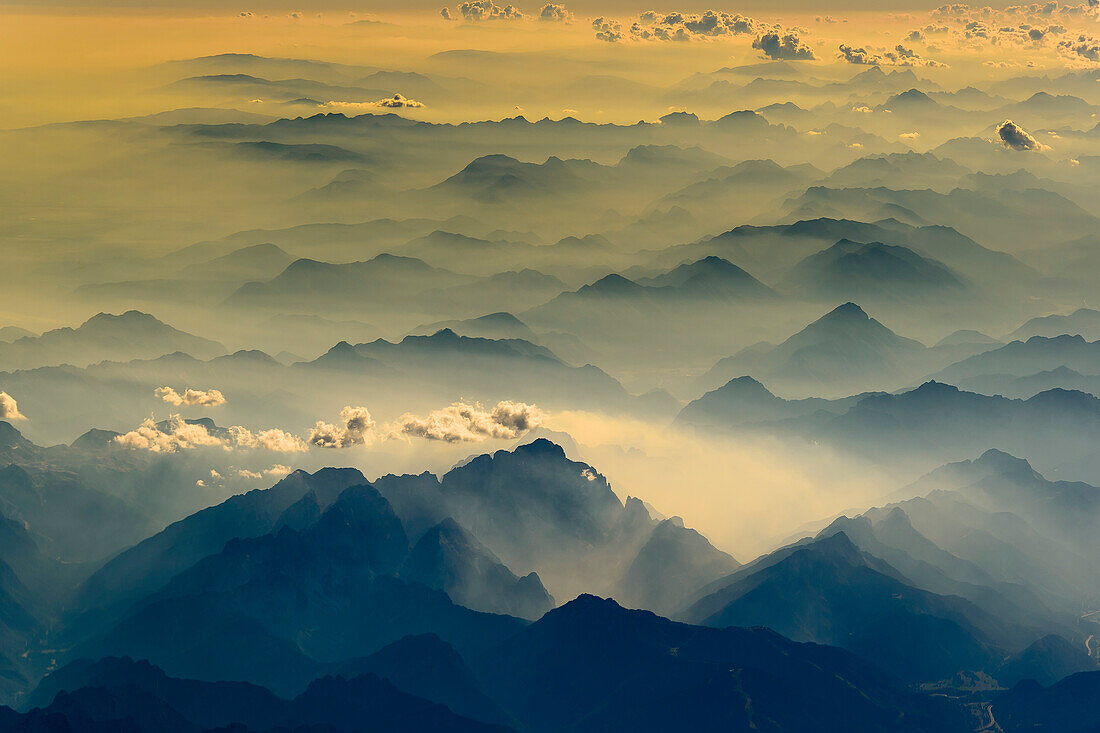 Dunst in den Tälern der Alpen verleiht der Lauftaufnahme eine räumliche Tiefe. Sonnenuntergang über dem Salzburger Land, Österreich