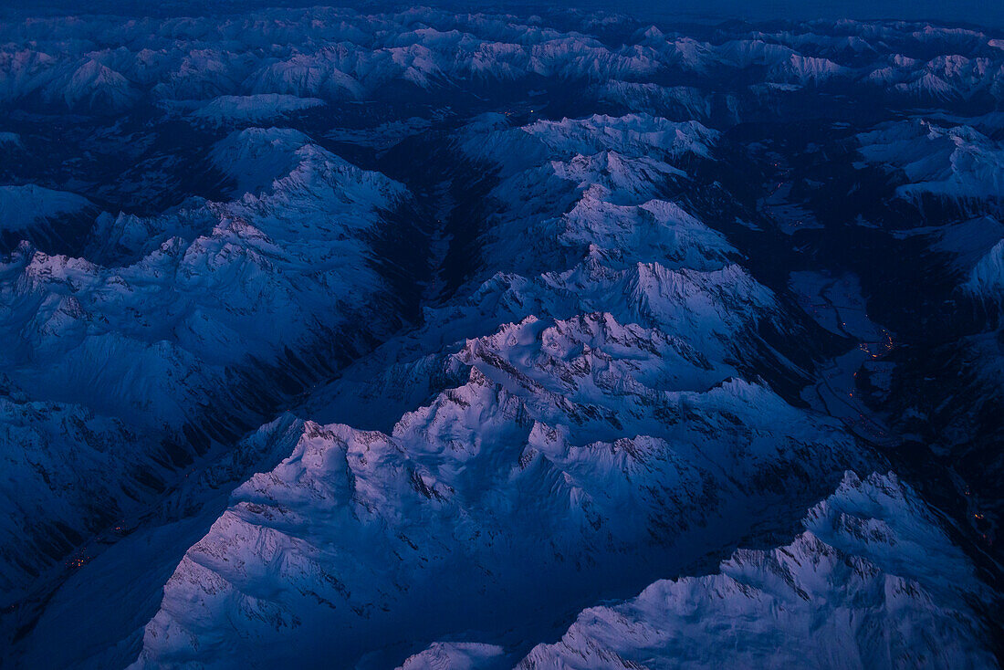 Erstes Licht am frühen Morgen bei einem Nachtflug über die Gipfel der Alpen Norditaliens, nördlich von Bergamo, Italien
