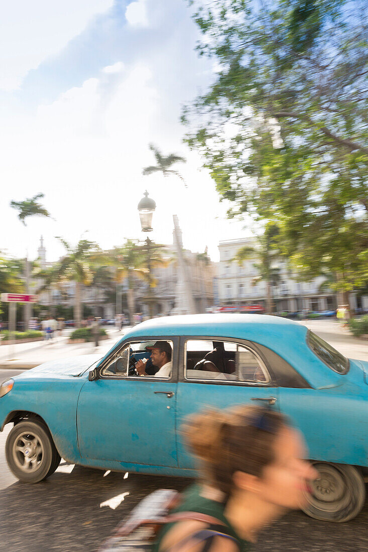blue oldtimer driving along Central Park, parque central, historic town, center, old town, Habana Vieja, Habana Centro, family travel to Cuba, holiday, time-out, adventure, Havana, Cuba, Caribbean island