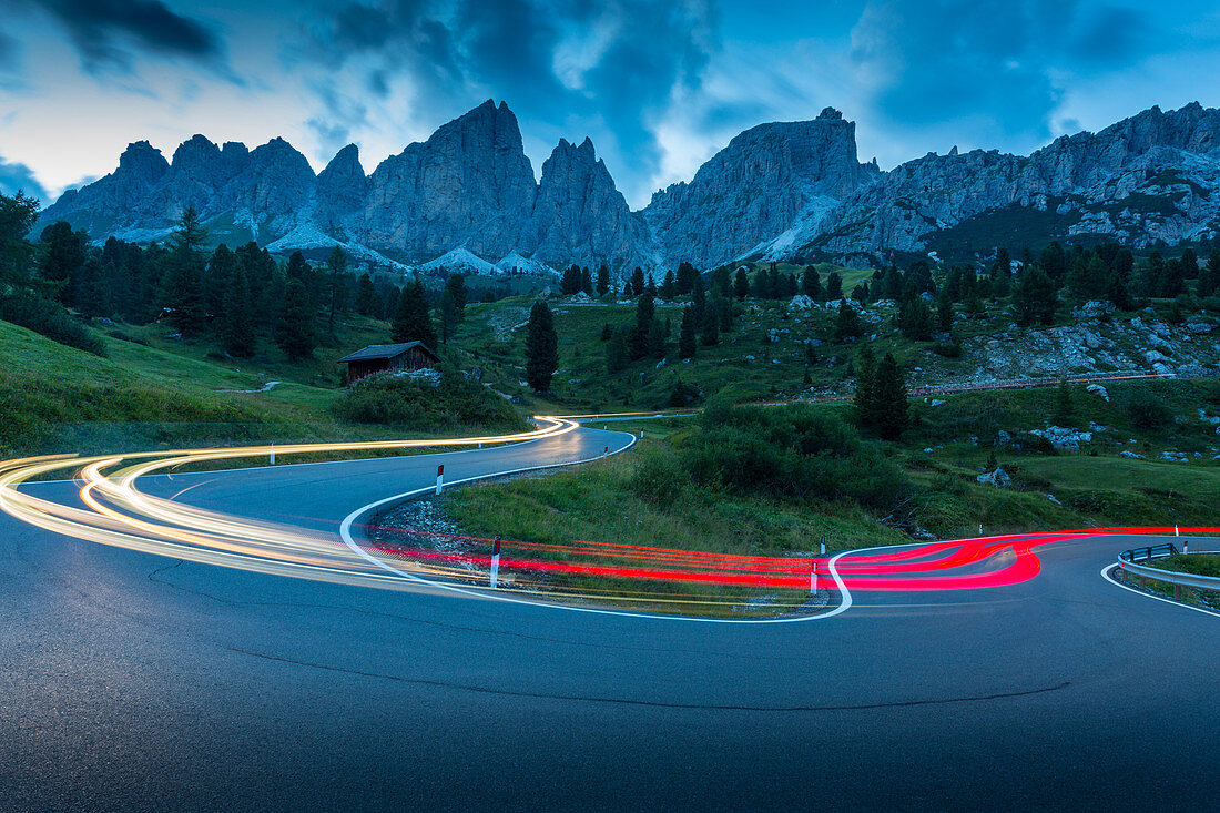 Car trail lights on Passo Pordoi with mountain backdrop at dusk, Province of Bolzano, South Tyrol, Italian Dolomites, Italy, Europe