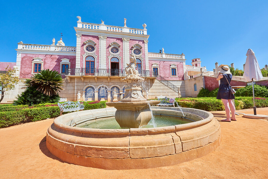 A tourist takes a photo at the entrance of Estoi Palace, in the Algarve, Portugal, Europe