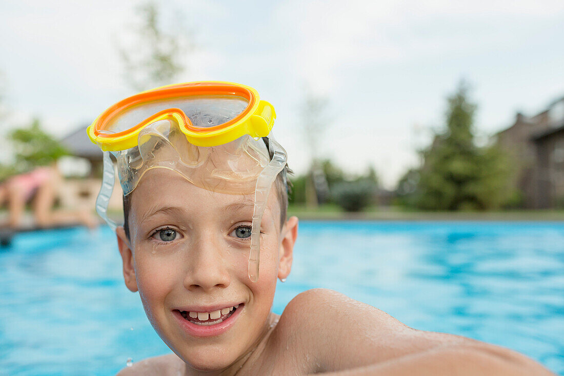Portrait of smiling shirtless boy with swimming goggles in pool