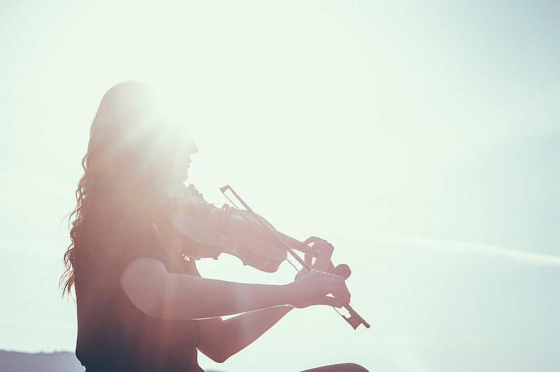 Niedriger Blickwinkel von Frau spielt Geige gegen den Himmel an einem sonnigen Tag