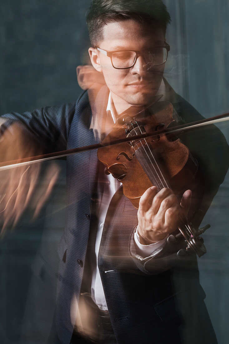 Blurred motion of violinist playing violin against wall