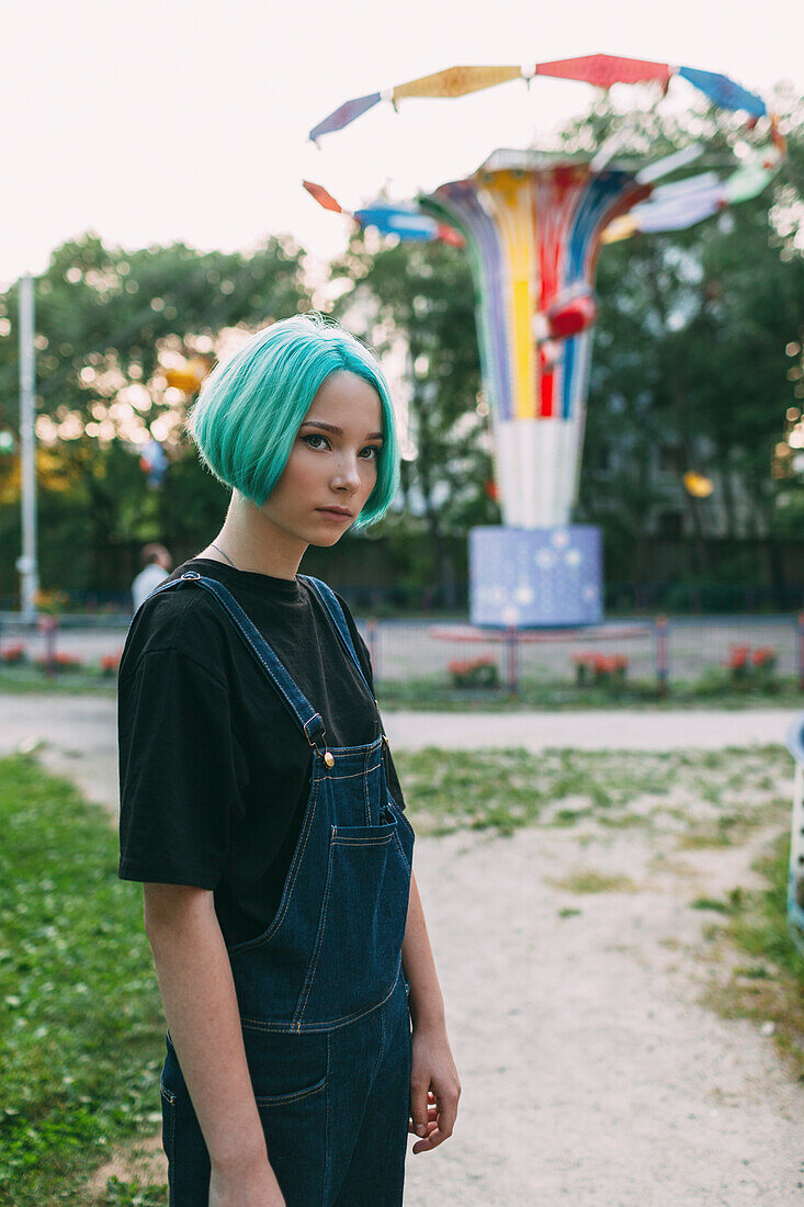 Portrait of teenage girl standing against amusement park ride