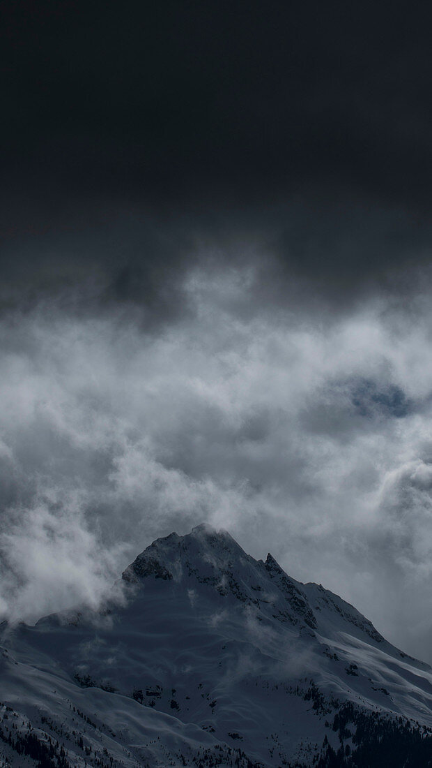 Low angle view of snowcapped mountain against cloudy sky, Tantalus, British Columbia, Canada