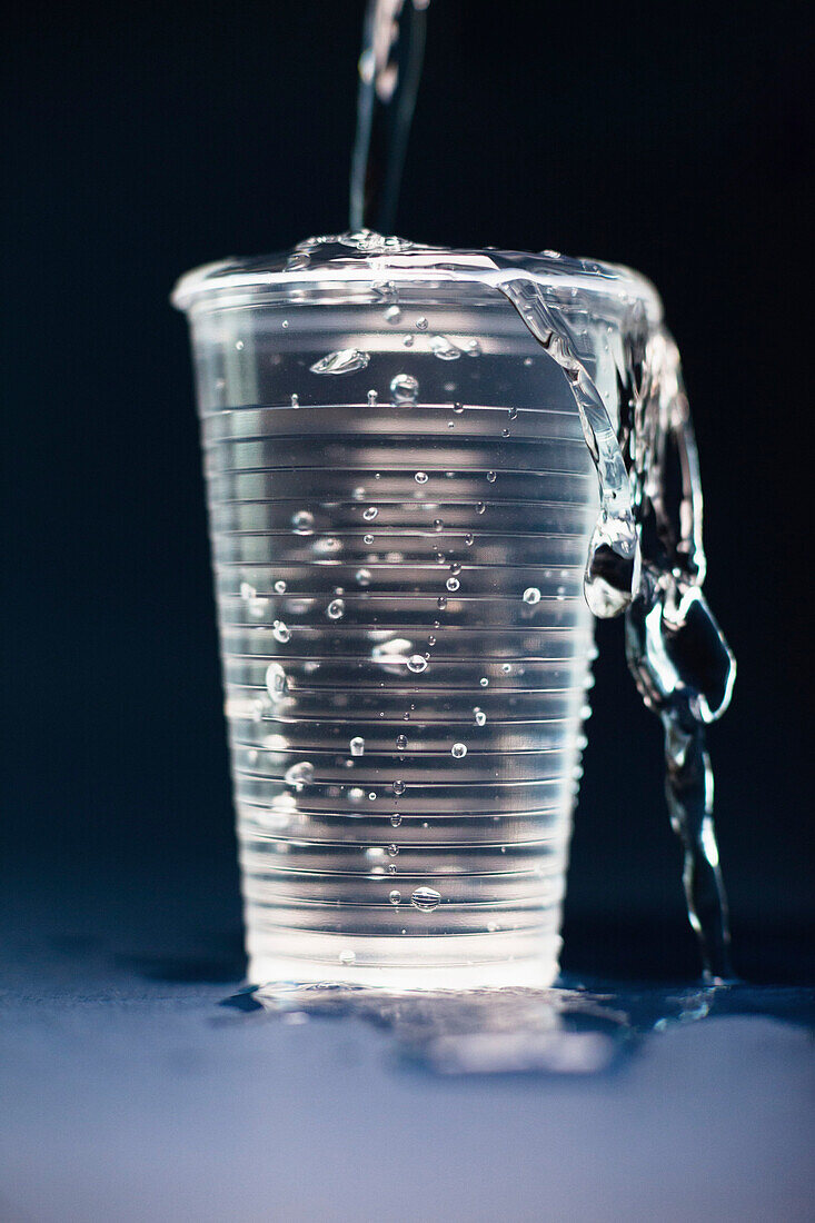 Close-up of water pouring in overflowing glass on table against black background
