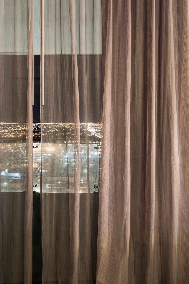 Illuminated city seen through curtains over window at night, Las Vegas, Nevada, USA