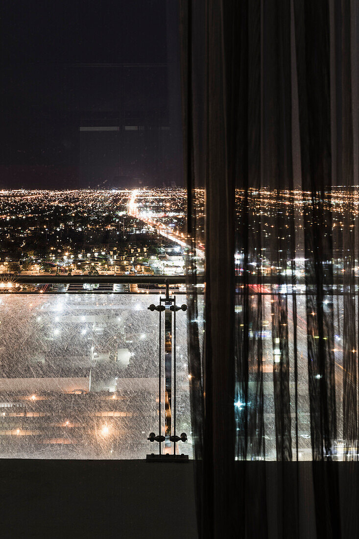 Illuminated cityscape seen through curtains on window, Las Vegas, Nevada, USA