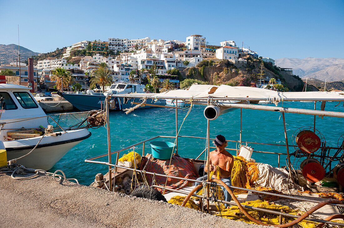 Fisherman and fishing boat in the harbour, Agia Galini, Crete, Greece, Europe